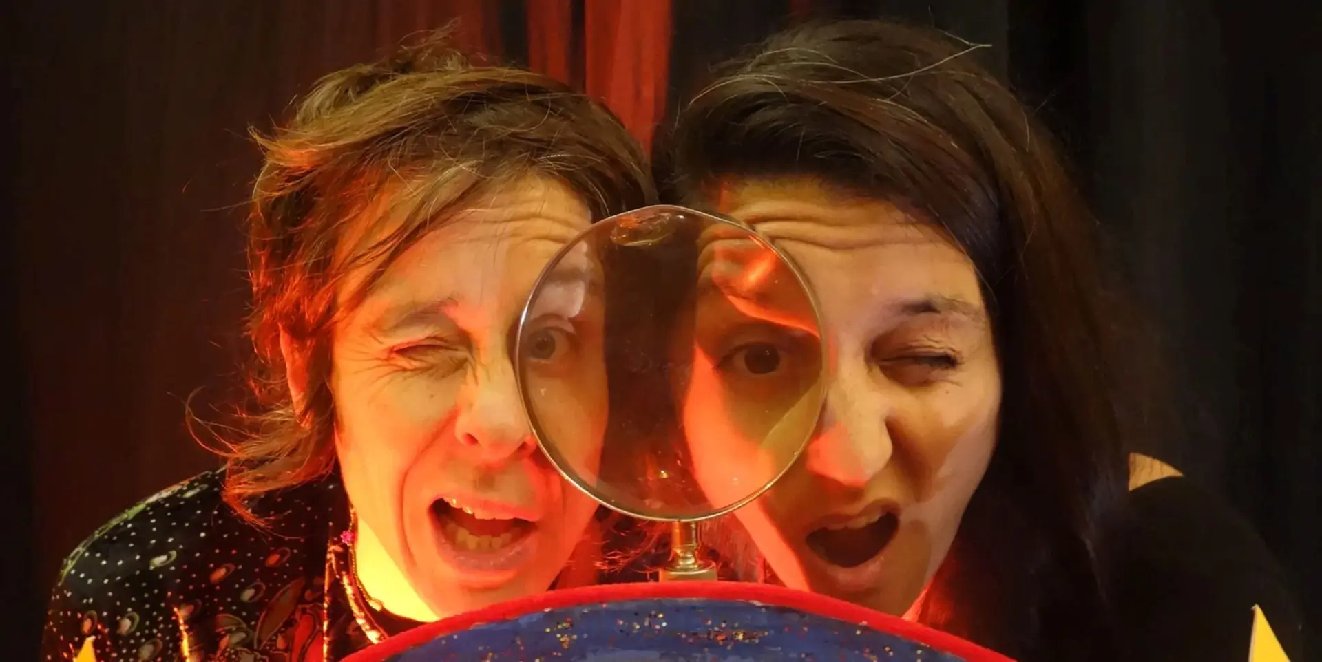 2 artistes derrière une grosse loupe