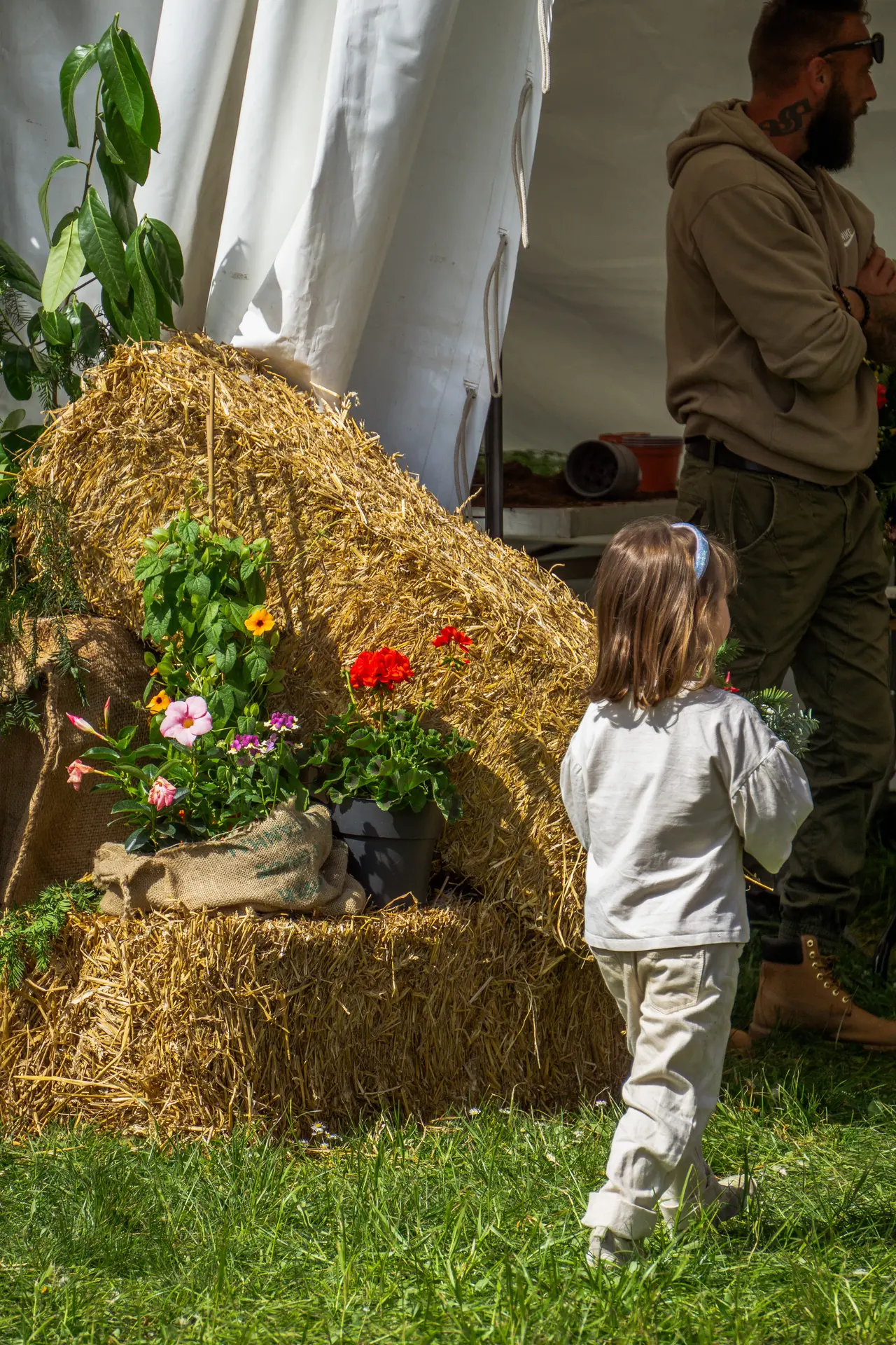 Une petite fille de dos, devant une botte de paille
