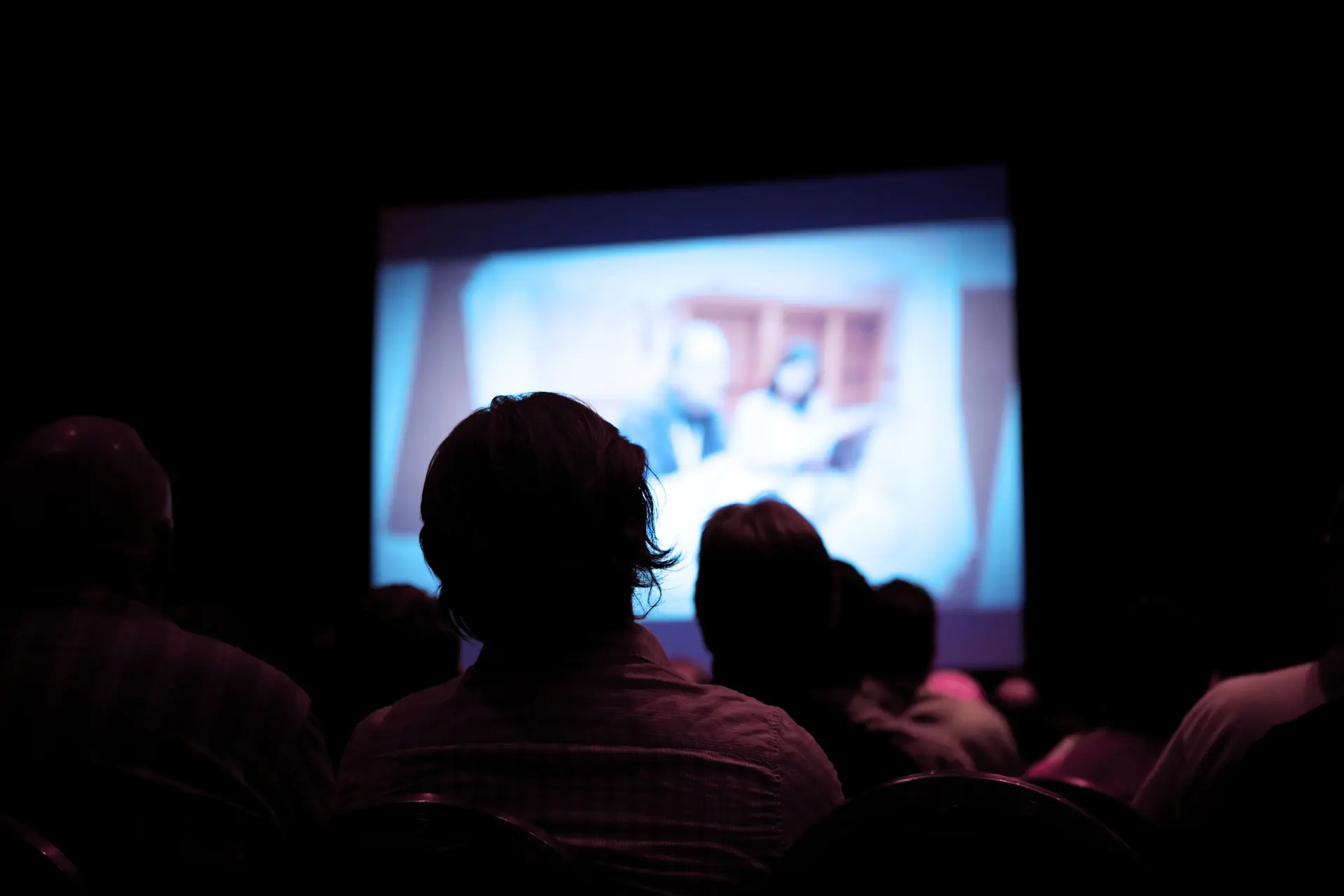 Couple assis dans le noir regardant l'écran d'un cinéma