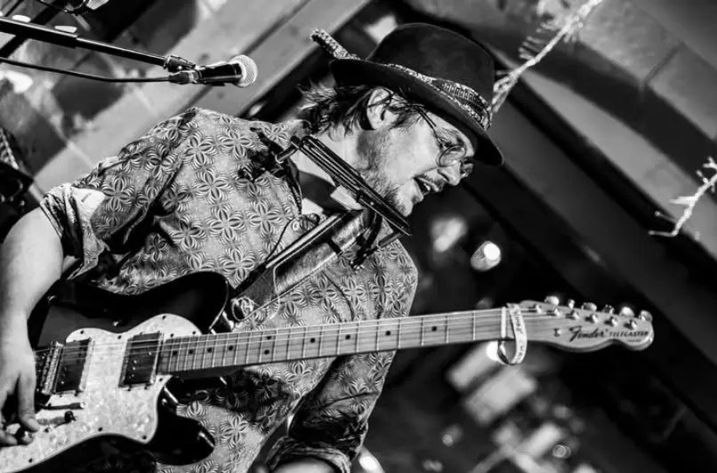 Photo en noir et blanc du guitariste avec un chapeau en concert