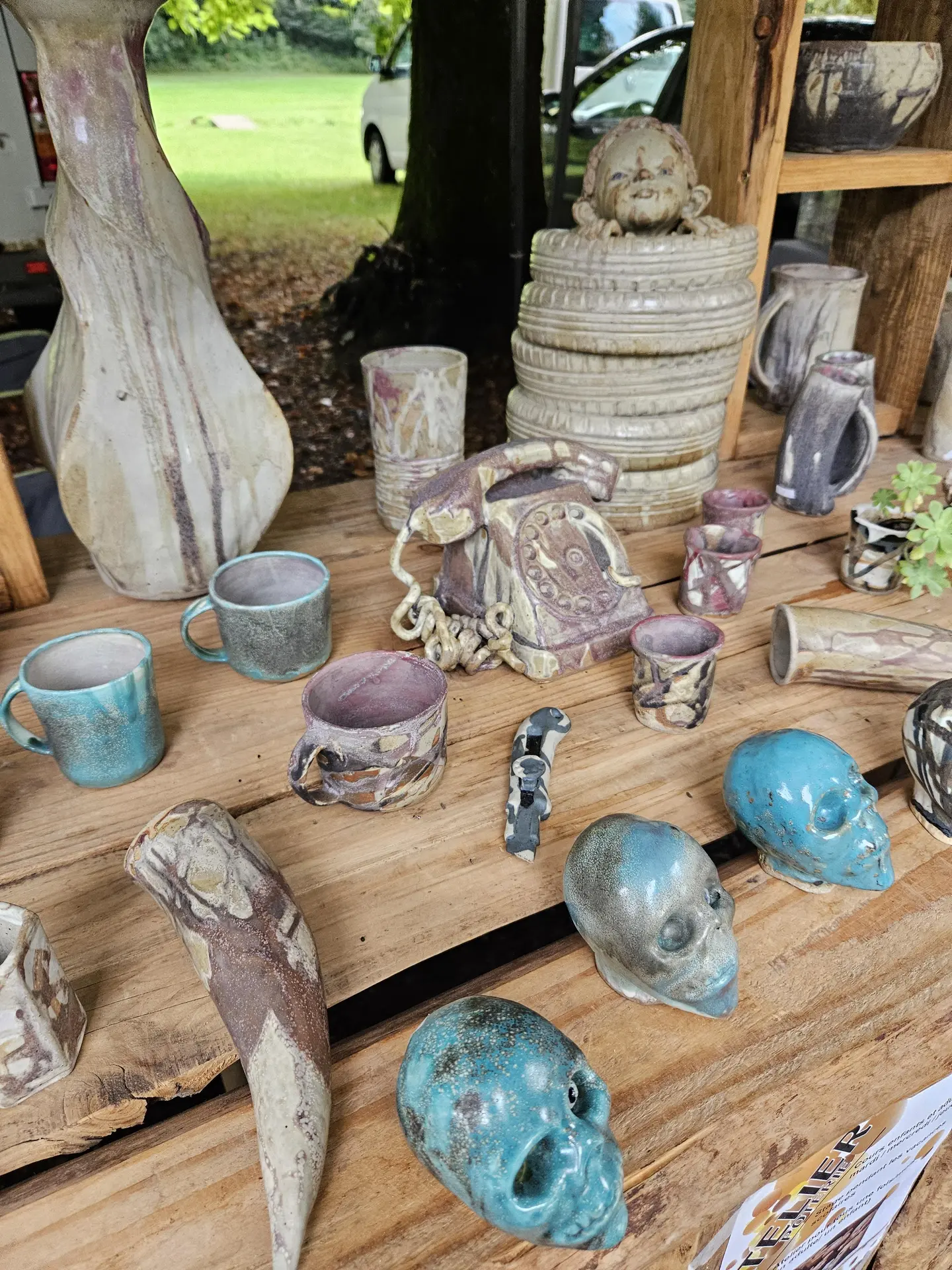 Un stand d'exposition de poterie avec des tasses bleues et des cranes miniatures.