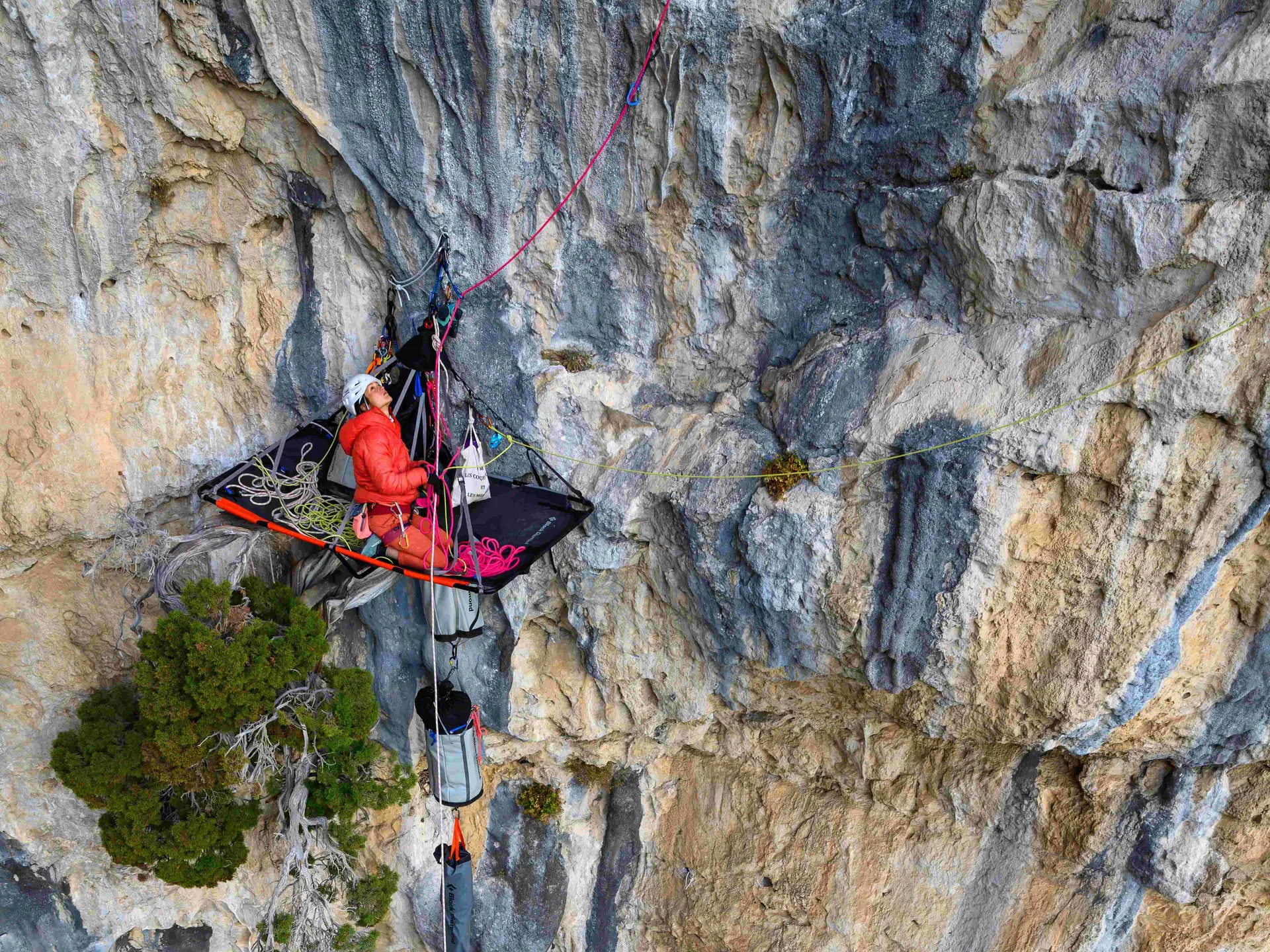 Une femme accrochée à une paroi rocheuse verticale.