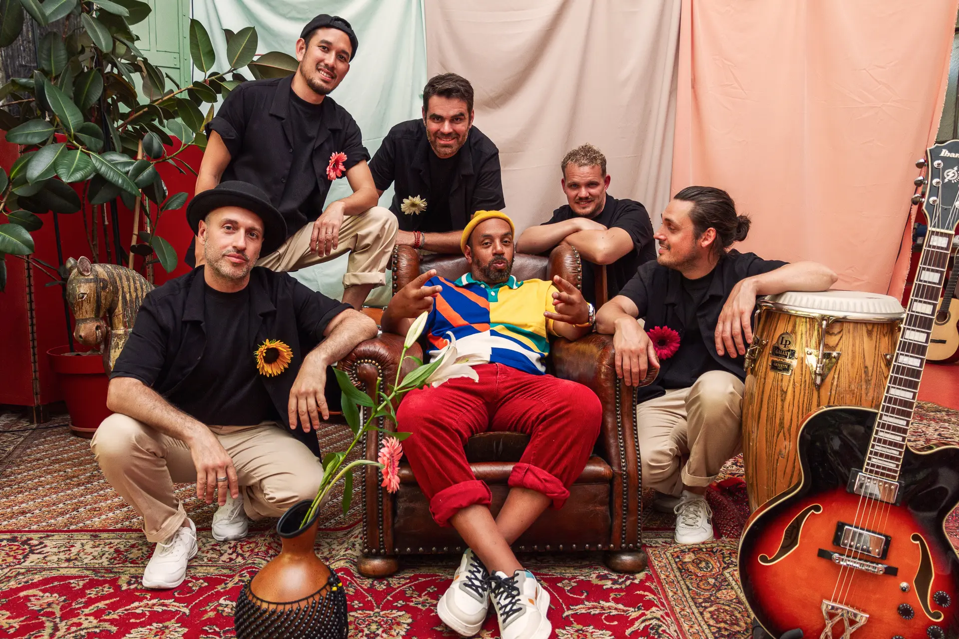 Groupe de musicien avec une personne dans un fauteuil et les autres musiciens autour de lui