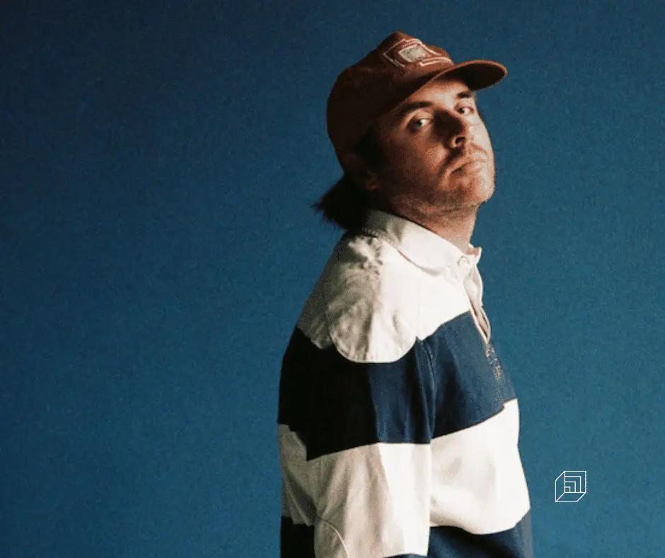 l'artiste portant un sweat rayé et une casquette