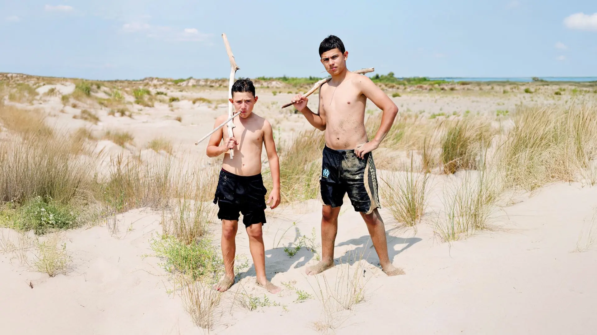 photos de 2 garçons dans un paysage de dunes qui tiennent des bâtons