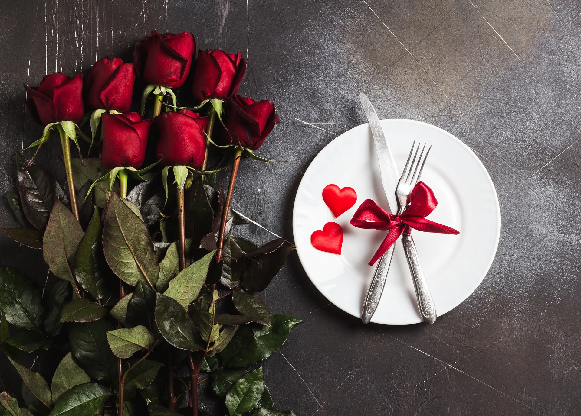 Un bouquet de roses rouges à côté d'une assiette