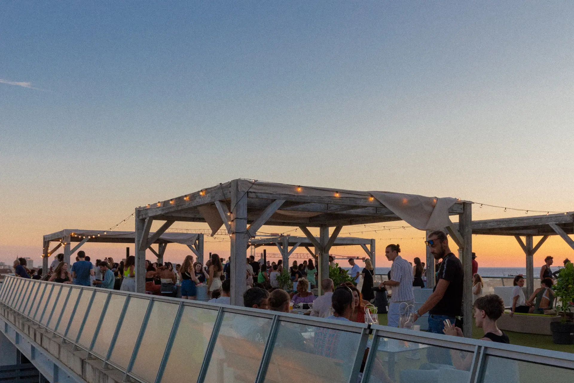 photo d'une pergola en hauteur sur un toit avec des loupiottes au coucher du soleil