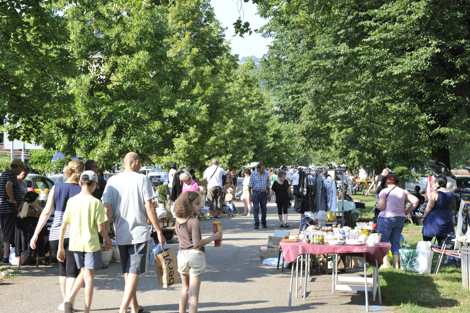Des promeneurs flânent au vide-greniers dans le parc d'Uriage