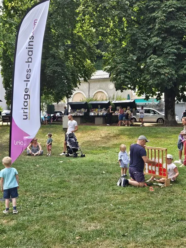 Plusieurs enfants avec leurs parents jouant à des jeux géants en bois dans un parc.
