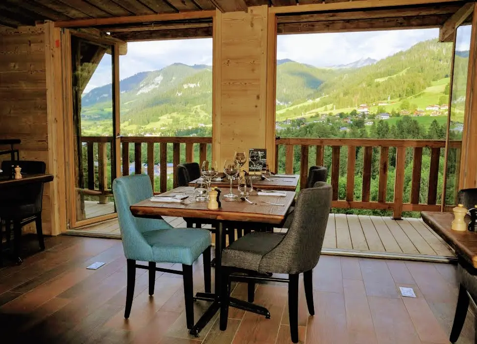 Table du restaurant devant une baie vitrée donnant sur les paysages verdoyants alentour