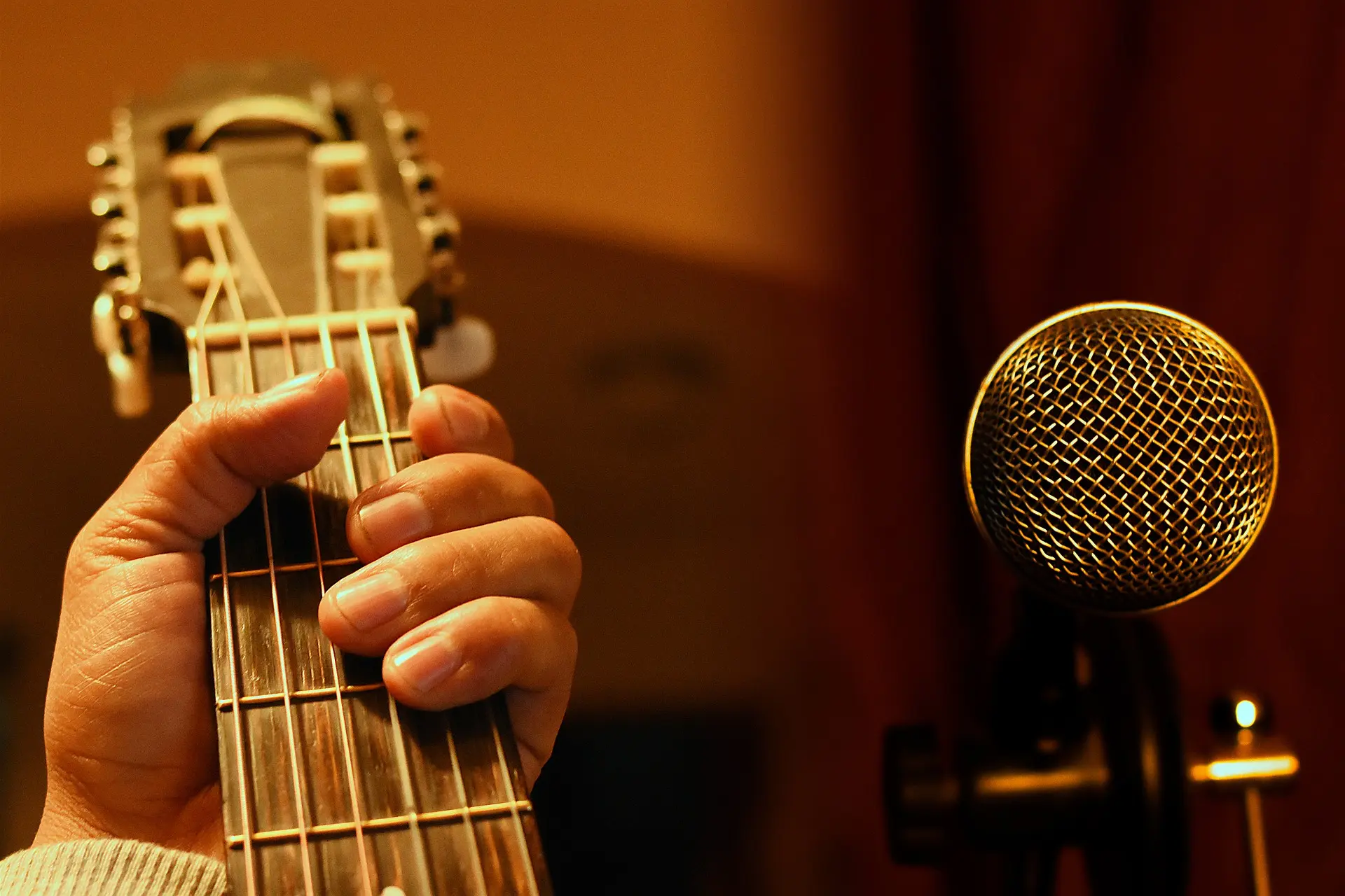 une main posée sur une guitare et un micro
