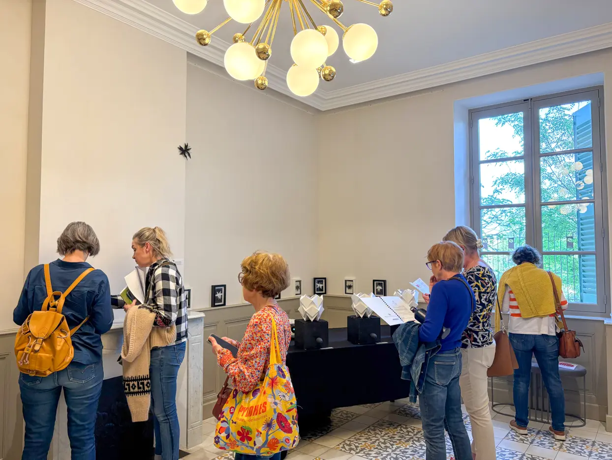 Groupe de visiteurs découvrant une exposition dans une salle intérieure, observant des œuvres et lisant des supports de médiation culturelle