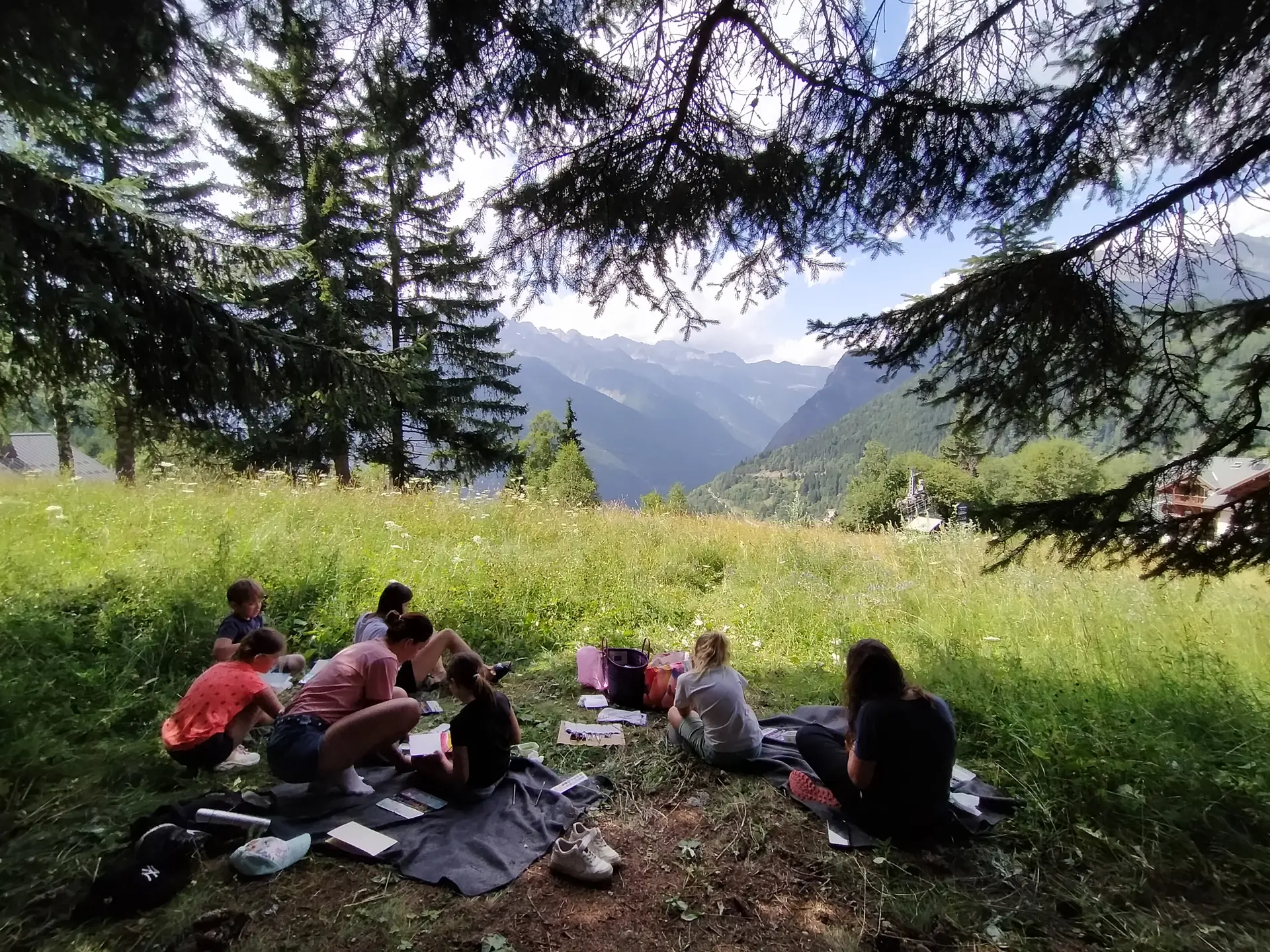 Un groupe assis dans l'herbe peint des aquarelles des montagnes environnantes.