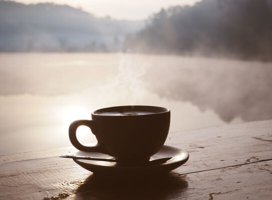 Silhouette cup of coffee at sunrise in the morning