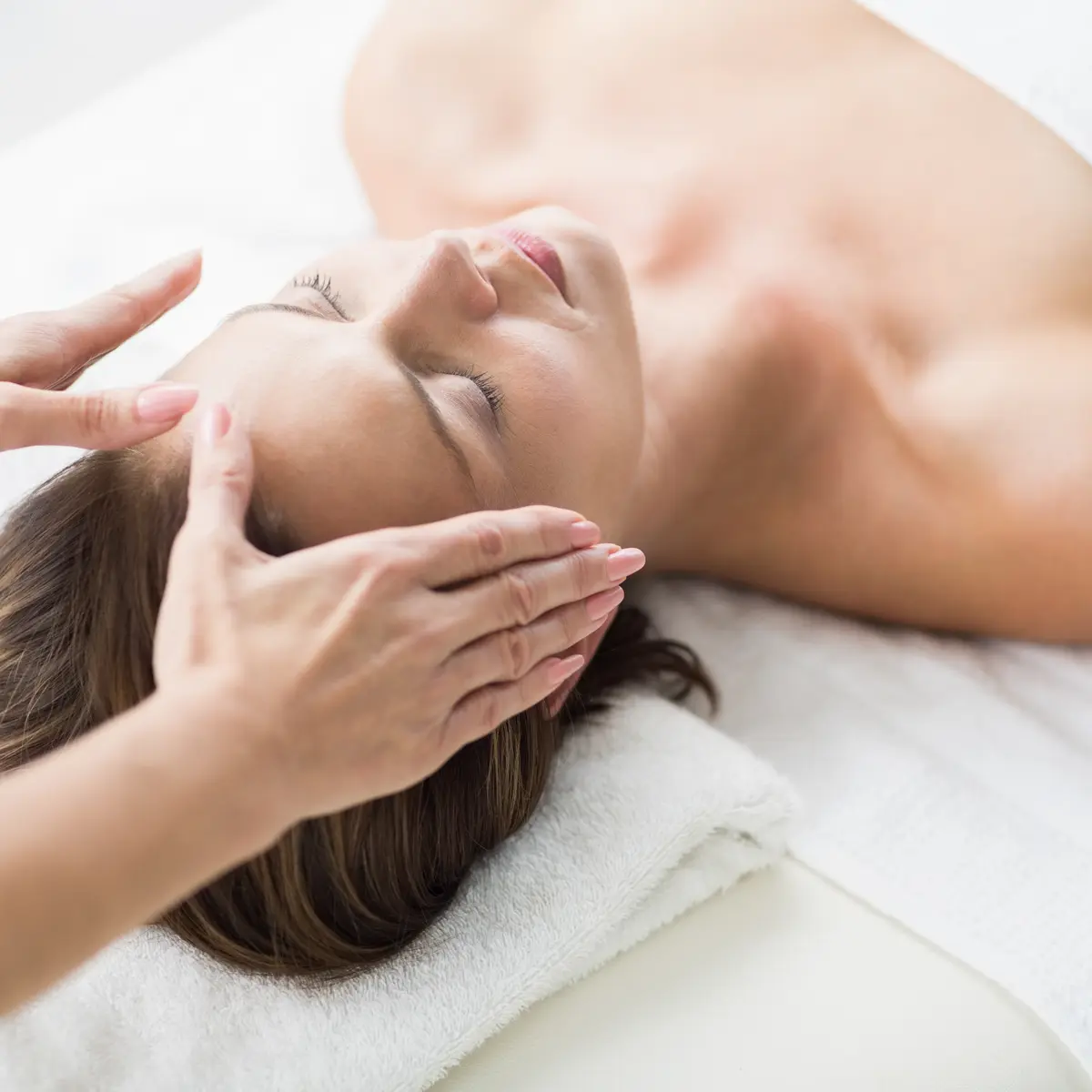 Cropped hands of therapist performing reiki on woman