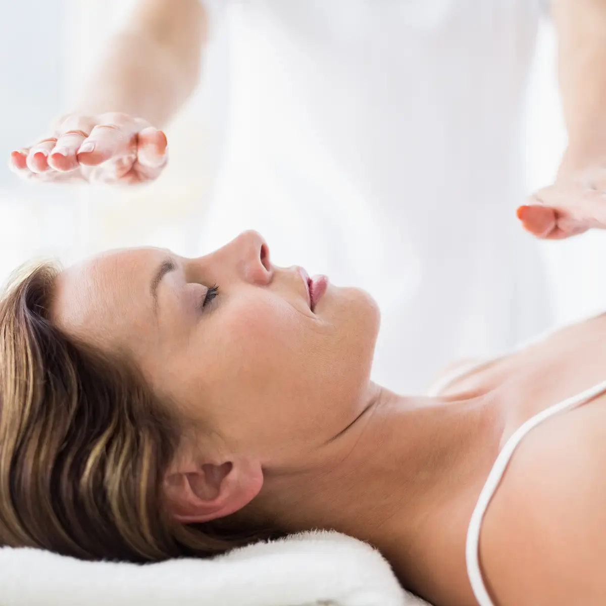 Midsection of therapist performing reiki treatment on woman