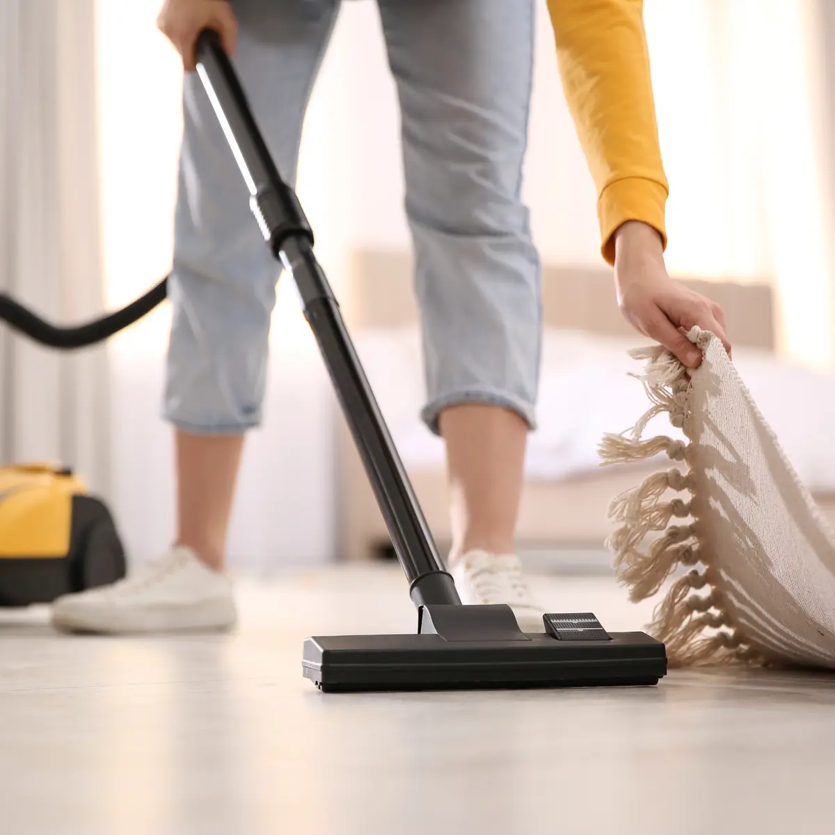 Young woman using vacuum cleaner at home, closeup