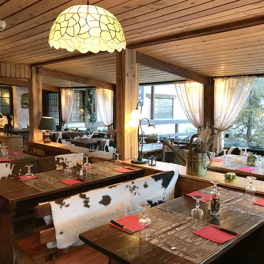 Salle intérieure du restaurant, tables et chaises, ambiance chalet et décor de montagne
