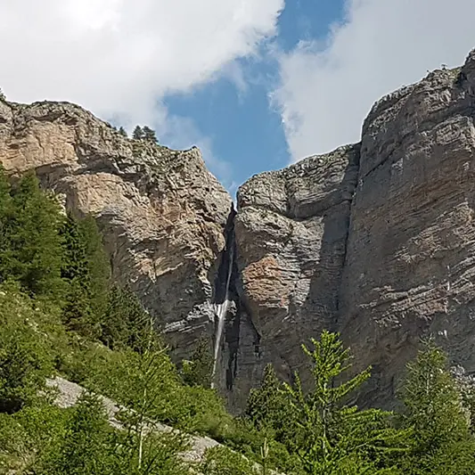 Vue de la cascade du Pich, située dans une crevasse rocheuse à côté d'une forêt de conifères