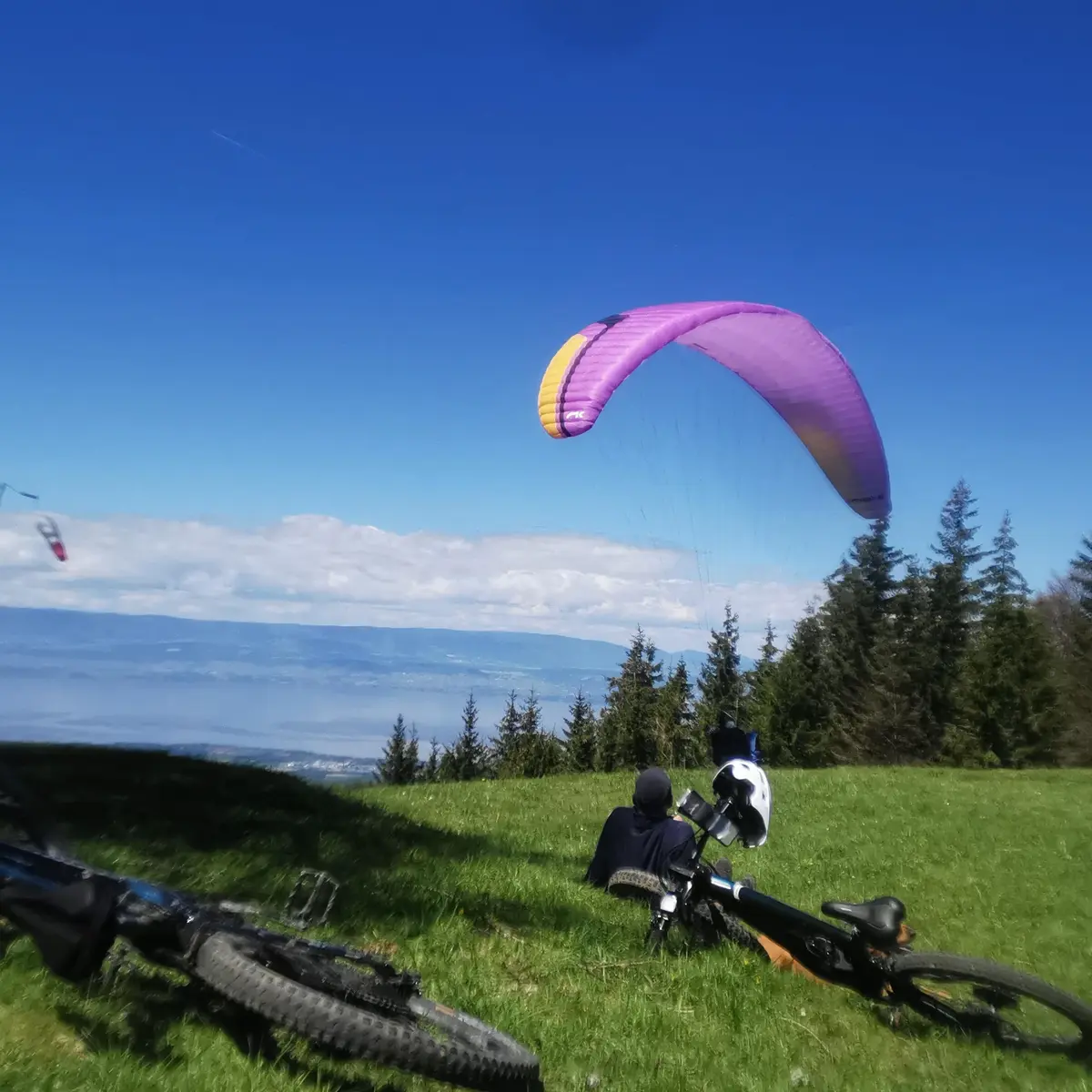 vtt et parapente sur l'aire de décollage avec vue sur le Léman