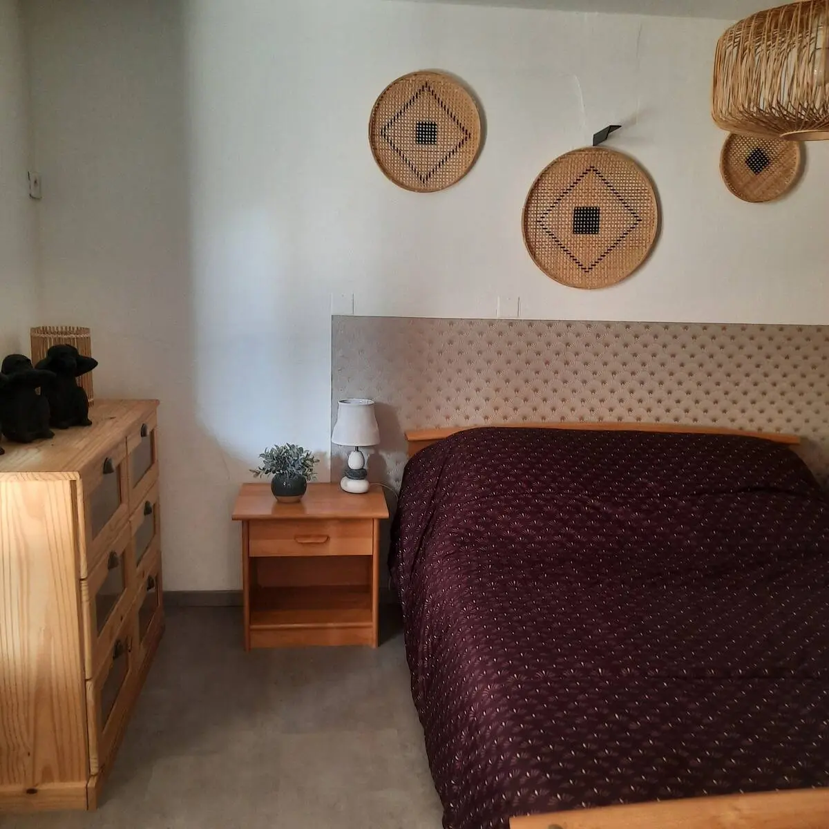 Chambre décoré simplement avec des draps marrons et un mur blanc.