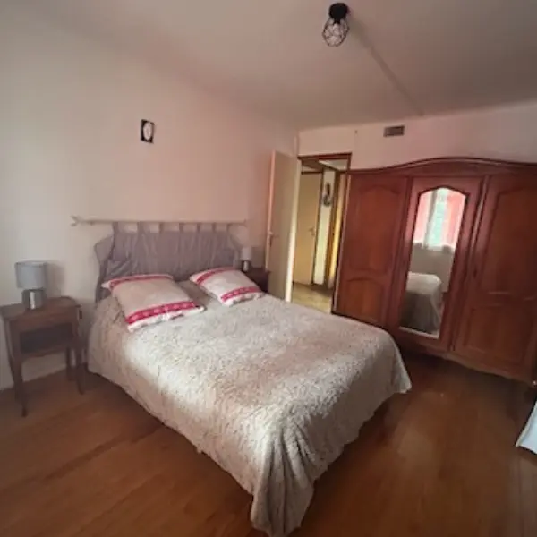 Bright room with wooden flooring and double bed. Tree door wardrobe with a mirror in the center