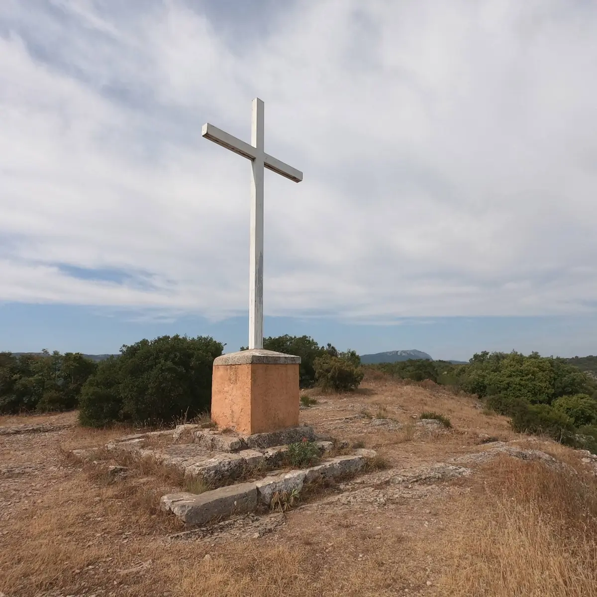 Croix blanche édifiée sur un plot béton à quelques mètres de la chapelle