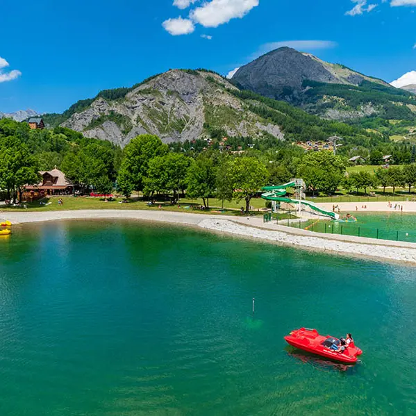 Aperçu des deux bassins du parc de loisirs d'Allos, gros plan sur le bassin aux pédalos, situé dans un cadre naturel avec montagnes boisées en arrière-plan