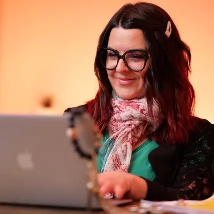 Une femme souriante travaille devant un ordinateur portable