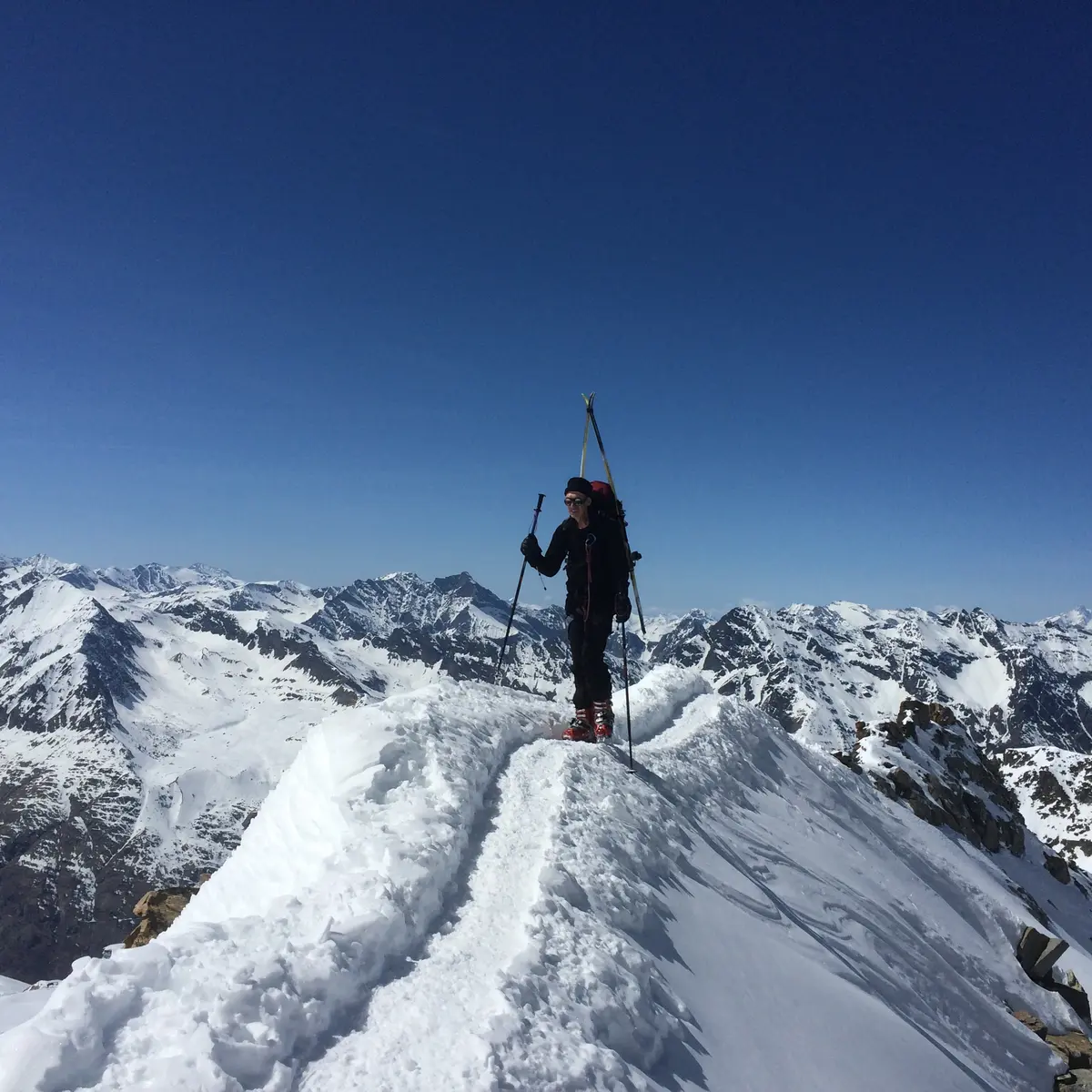 Skieur de randonnée au sommet d'une crete avec une vue panoramique sur les montagnes