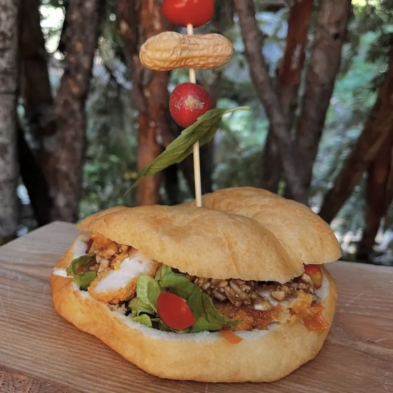 Sandwich avec poulet pané, salade, petite tomate, cacahuète