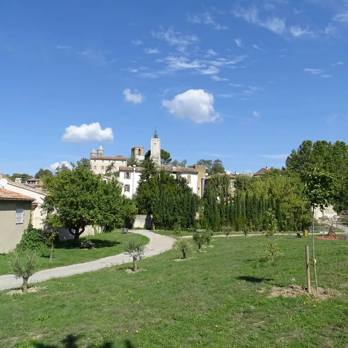 Vue sur le village avec son clocher en pierres et le parc arboré