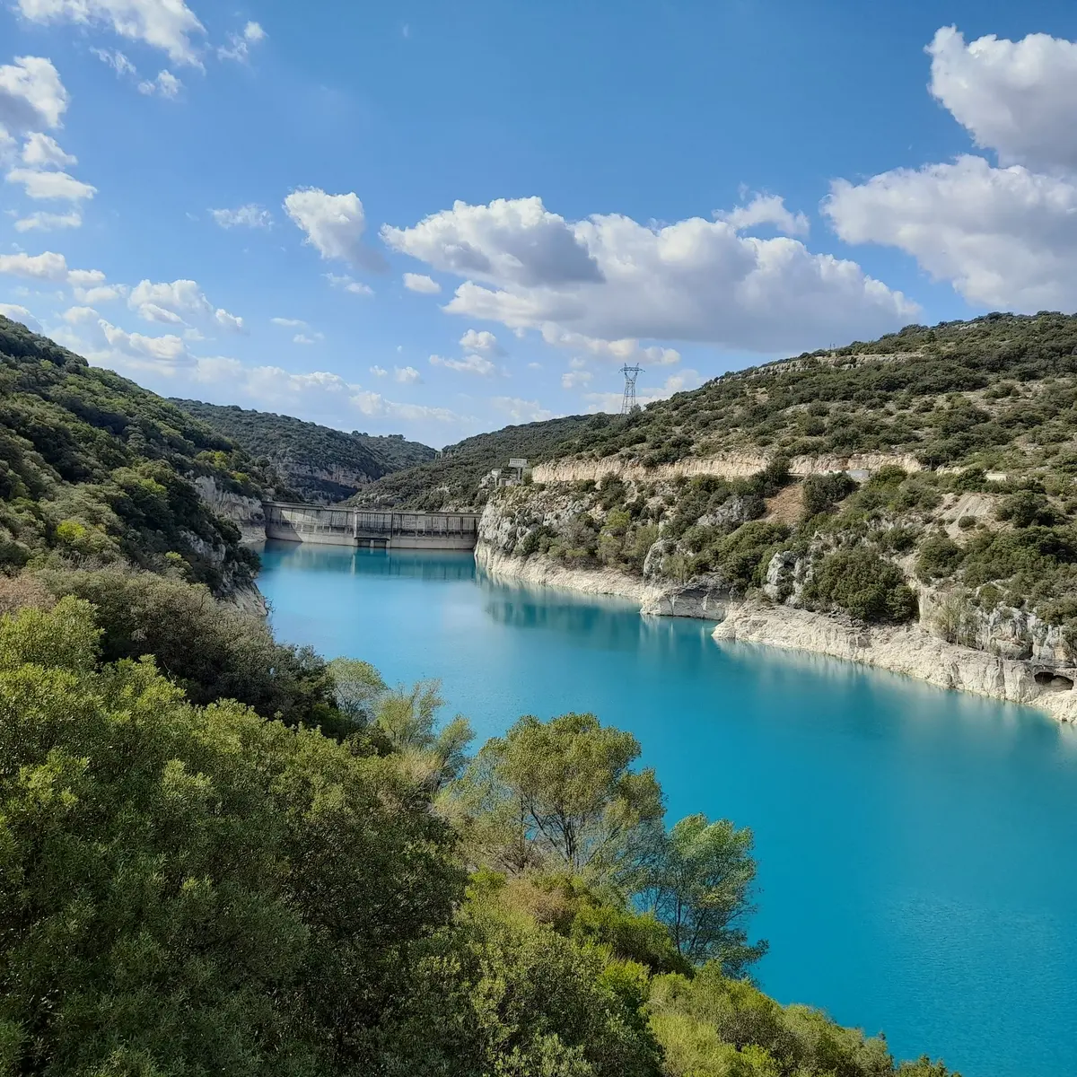 Vue sur le barrage, les berges calcaire et les eaux turquoises du lac entouré de végétation méditerranéenne