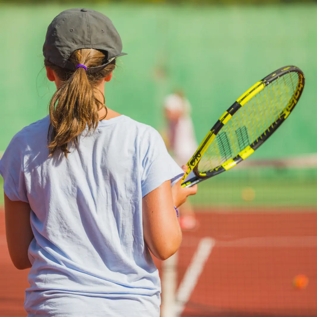 photo d'une jeune de dos tenant une raquette de tennis