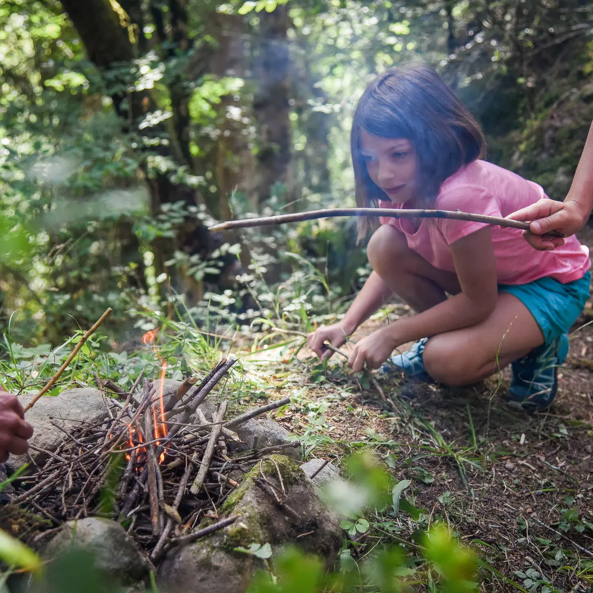 petite fille qui allume un feu de bois en forêt