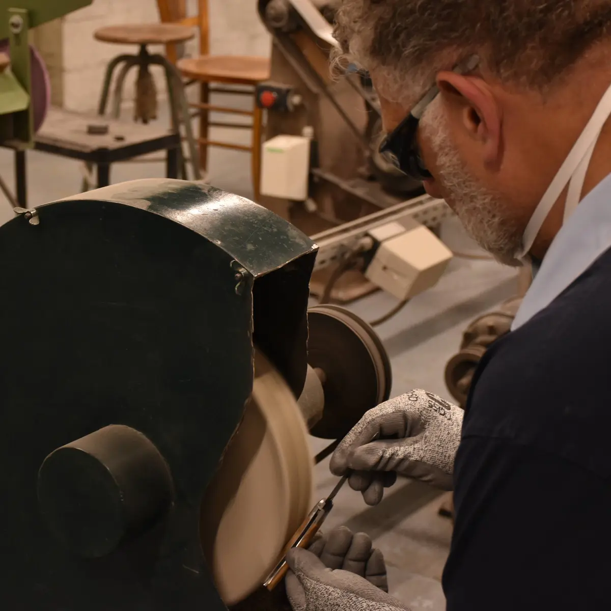 On voit la manière dont le coutelier meule le manche en bois du couteau