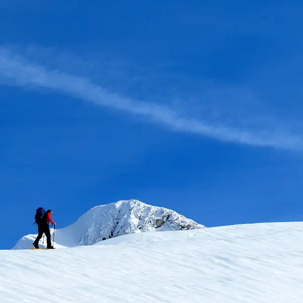 Promeneur en raquette dans un paysage ensoleillé et enneigé
