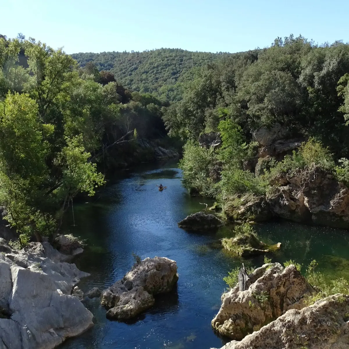 Vue sur la rivière entourée de rochers blancs et de végétation verdoyante