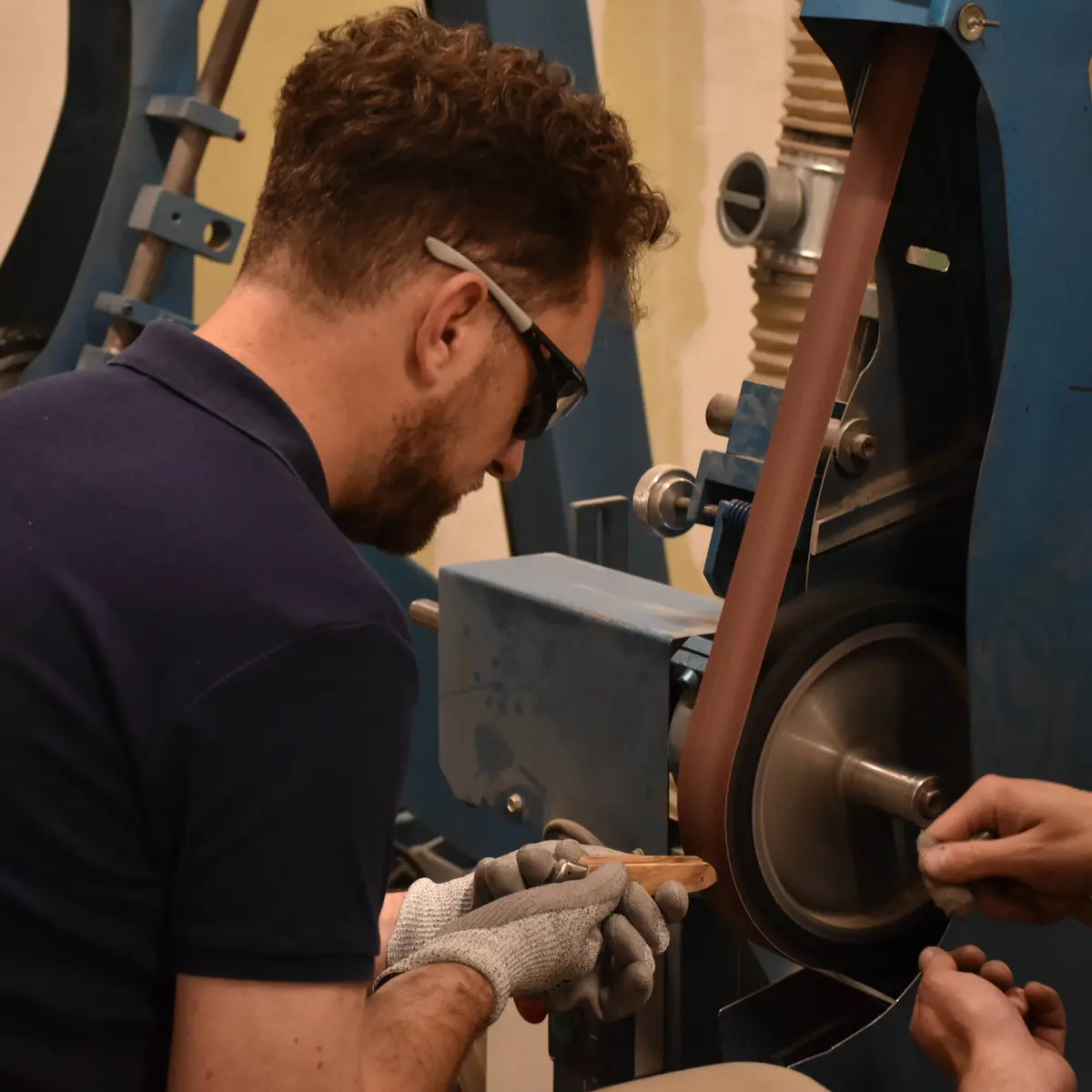 On voit la manière dont le coutelier meule le manche en bois du couteau
