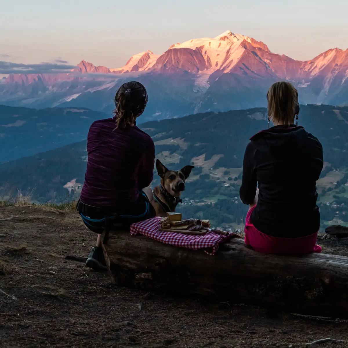 Deux randonneuses en train de pique-niquer face aux montagnes au coucher du soleil