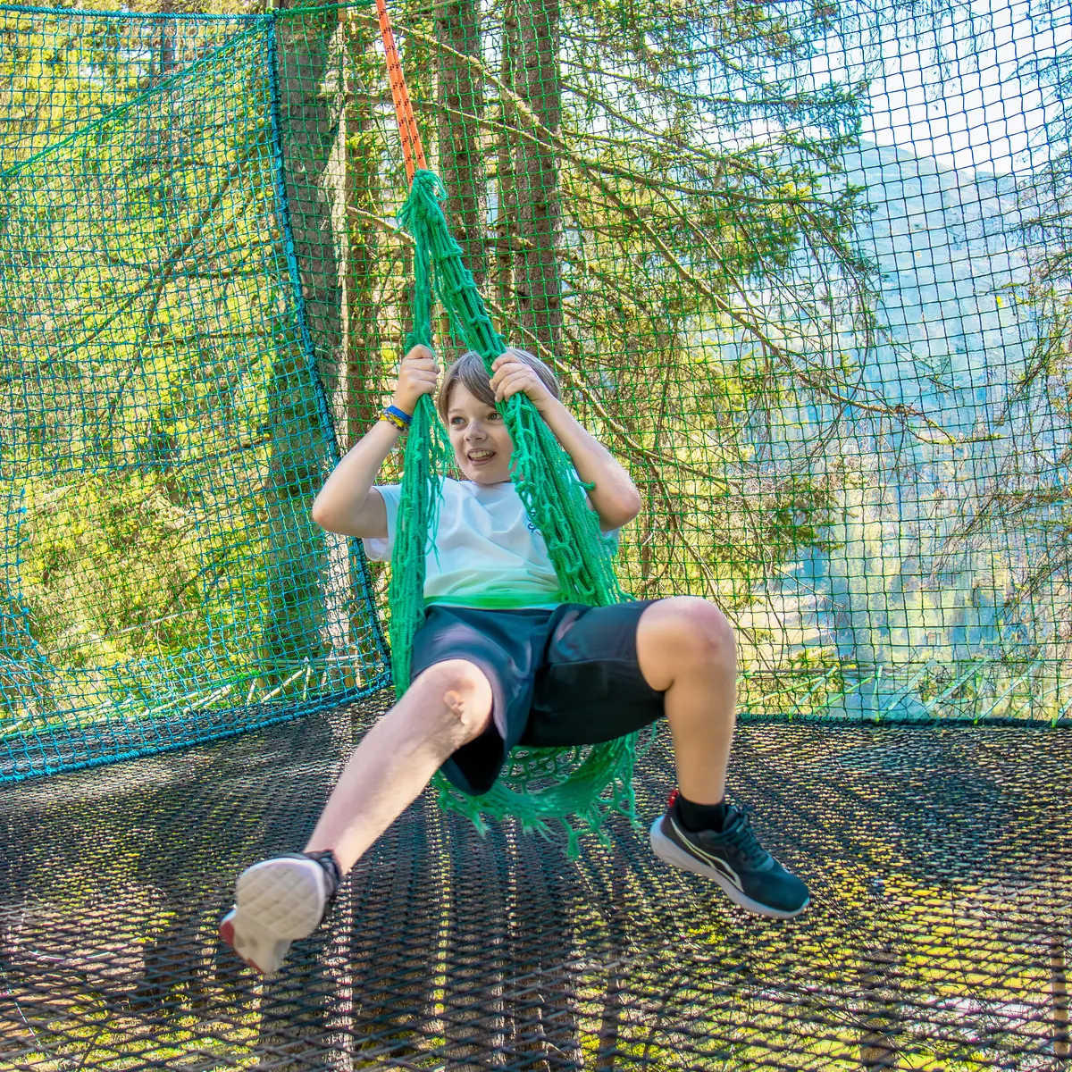 Un enfant assis sur la balançoire de l'accro-fun