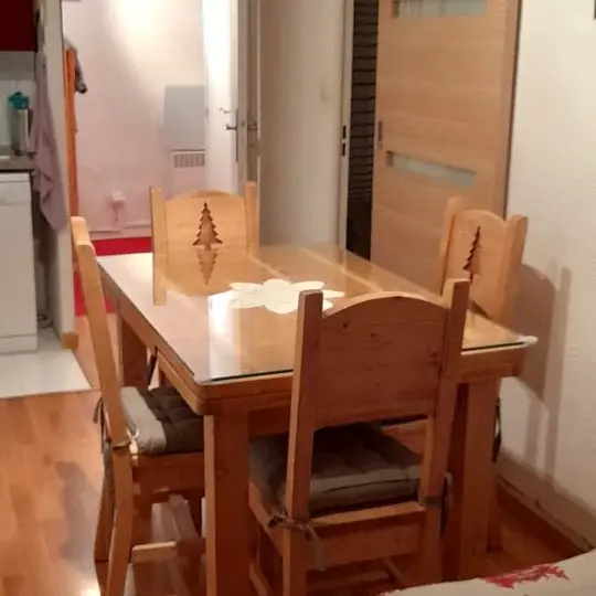 Séjour lumineux avec canapé, table à manger, coin cuisine, ameublement bois, parquet au sol