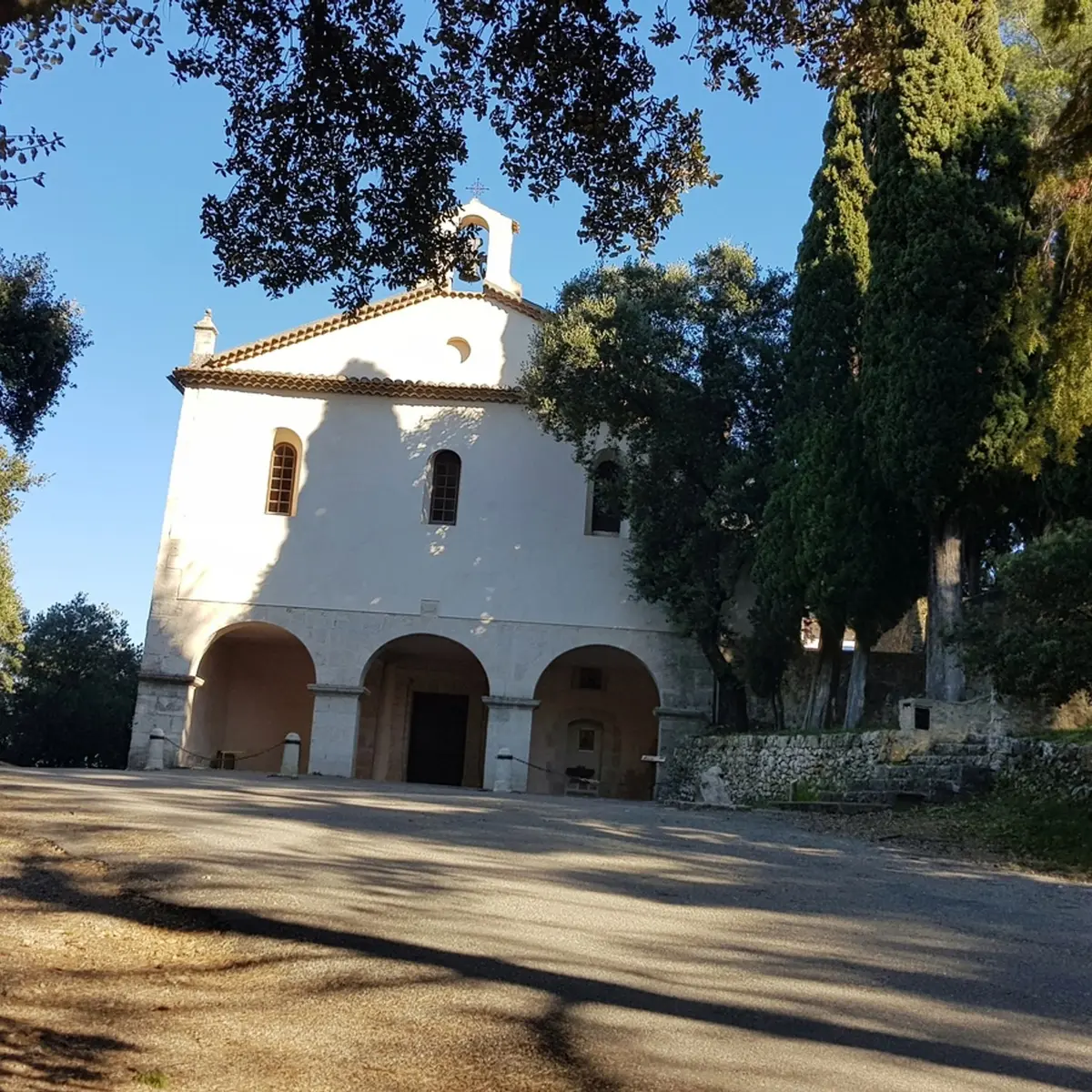 Chapelle à la façade blanche composée de 3 ouvertures voutées et 3 fenêtres avec vitraux et un petit clocher au sommet