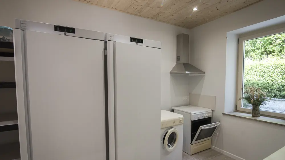 Cellier ou arrière cuisine avec 2 grands réfrigérateurs pros, un deuxième pôle cuisson, un point eau et une grande étagère de stockage