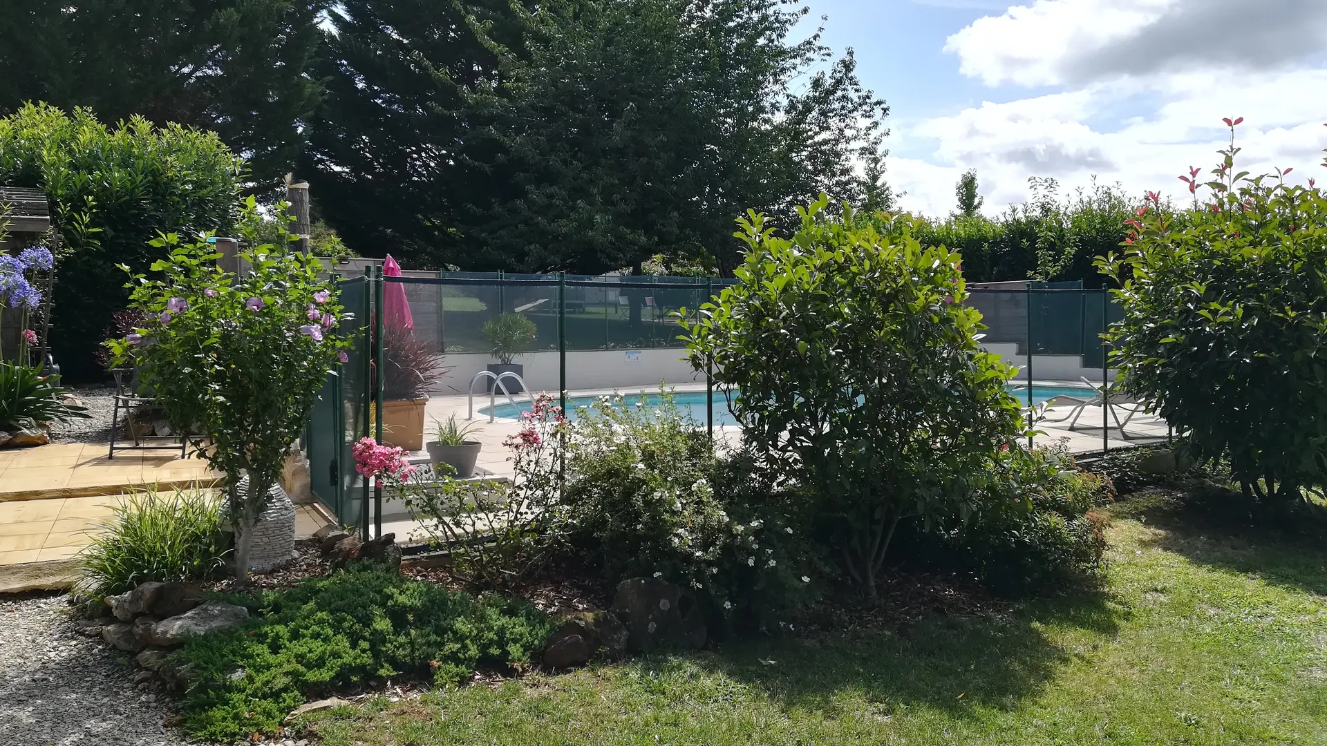 Accès à la piscine dans un écrin de verdure.