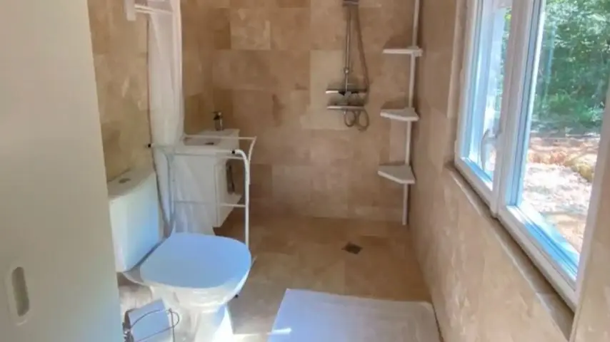 Salle de douche en marbre italien avec WC et vue sur les bois
