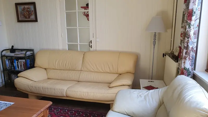 Vue sur salon, avec en arrière-plan porte vitrée donnant sur couloir d'accès