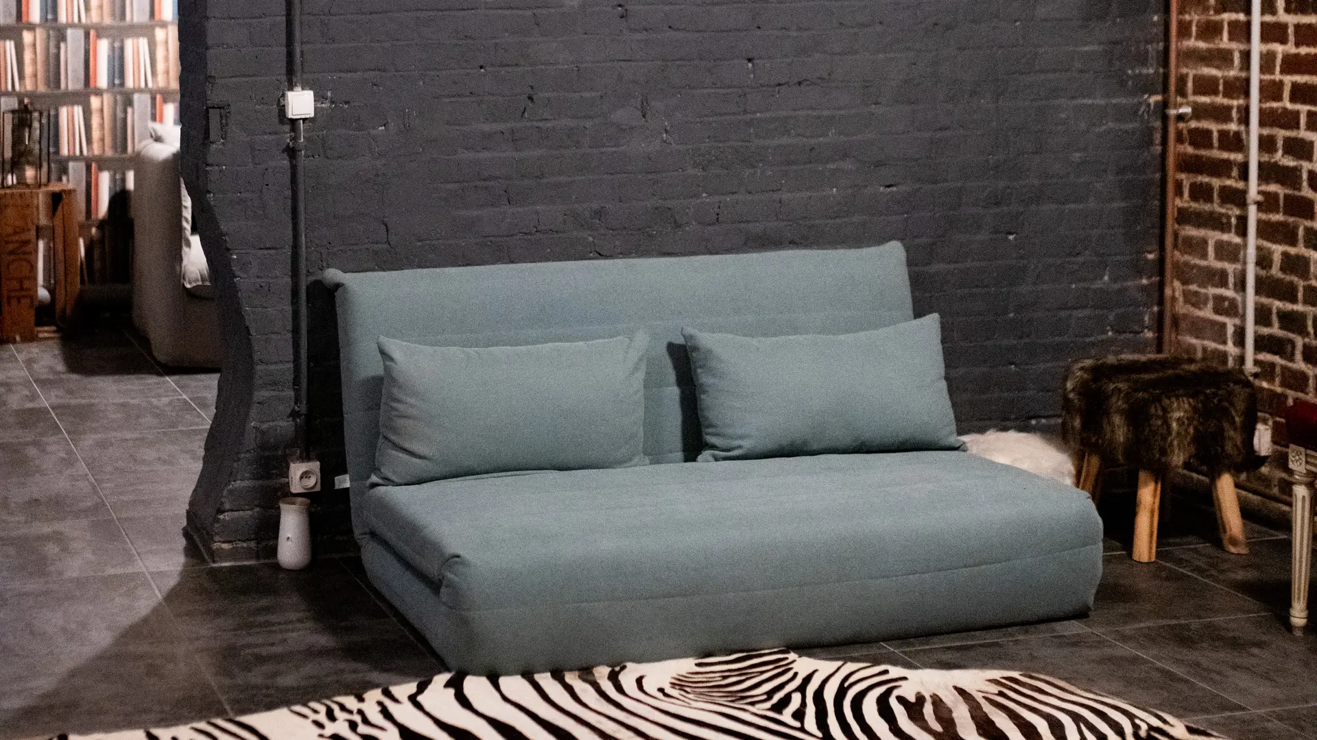 Sous sol aménagé avec canapé lit et coin lecture