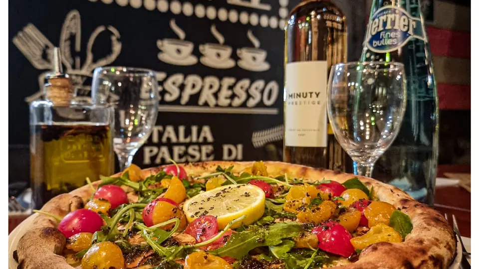 Pizzas fruits de mer avec un verre de vin blanc.