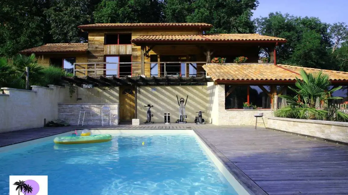 la piscine avec le gîte et la maison en arrière plan